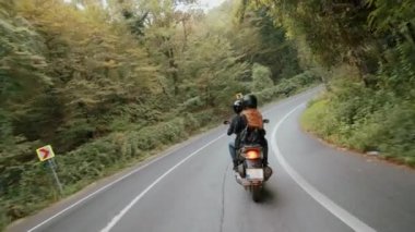 Bir dik alarak scooter üzerinde genç Kafkas çift doz yavaş yola dön. Arkadan vurdu.