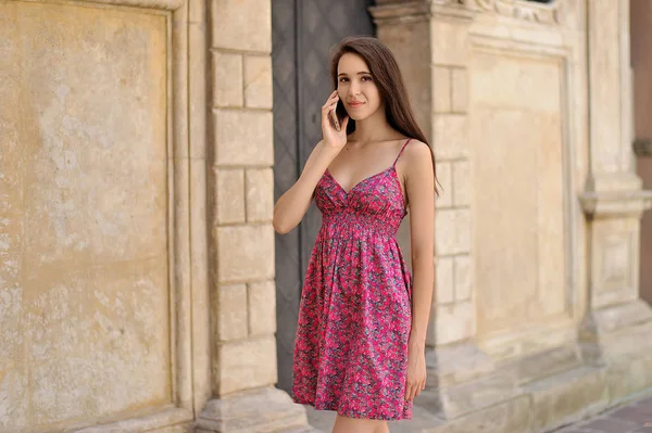 Gravid flicka talar via telefon på staden bakgrund — Stockfoto