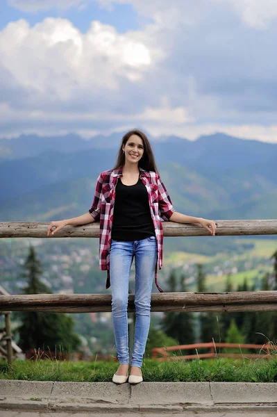 Chica feliz sentada en una valla sobre un fondo de montañas. Zako. — Foto de Stock