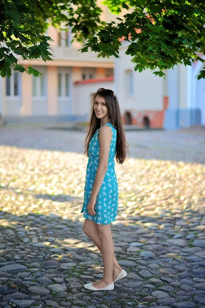 Joven chica sonriente en vestido de verano en el fondo del atardecer de la ciudad — Foto de Stock