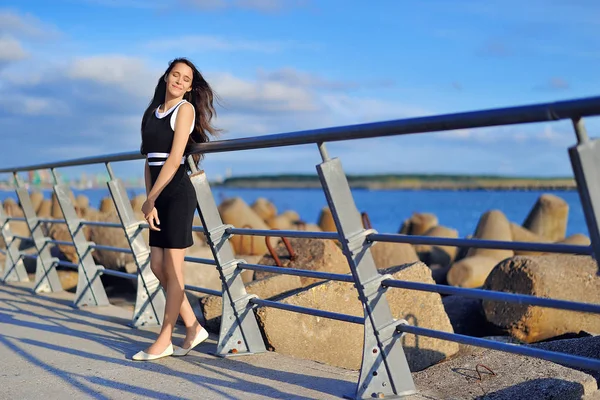 Siyah elbiseli güzel bir kız b bir iskelede duruyor