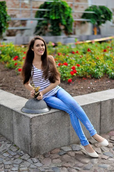 Krásná usměvavá dívka sedící vedle záhon venku — Stock fotografie