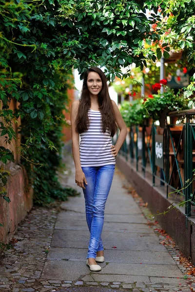 Una bella ragazza sorridente sta per strada contro lo schienale — Foto Stock