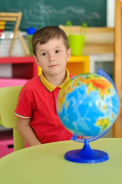 Хлопчик у дитячій кімнаті грає за столом з глобусом — стокове фото