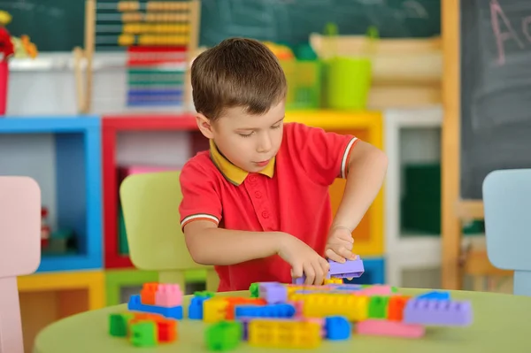 Мальчик в детской комнате играет за столом — стоковое фото