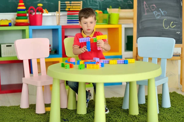 Um menino no quarto das crianças brincando na mesa — Fotografia de Stock