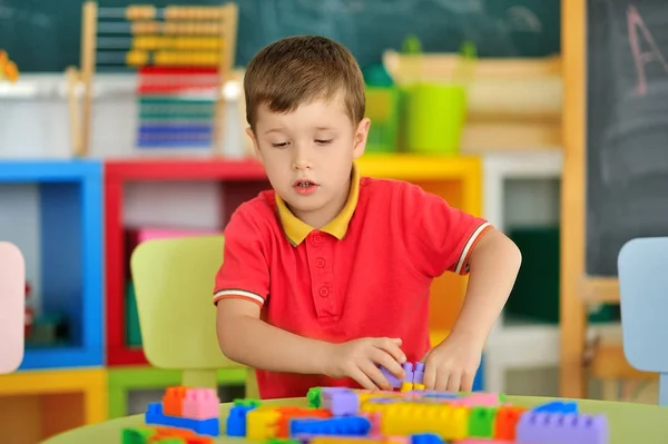 Um menino no quarto das crianças brincando na mesa — Fotografia de Stock