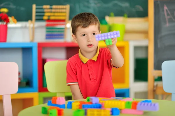 Um menino no quarto das crianças brincando na mesa — Fotografia de Stock