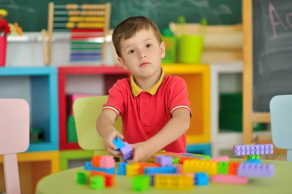 Um menino no quarto das crianças brincando na mesa — Fotografia de Stock