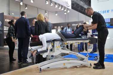 MEDICA Trade Fair, DUSSELDORF, GERMANY - NOVEMBER 2019, manual therapy, an instructor treats the back of a woman on a couch. clipart