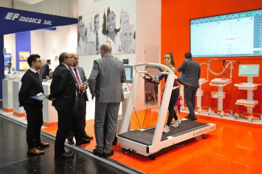 MEDICA Ticaret Fuarı, DÜKSELDORF, GERMANY - Kasım 2019, bir tıp sergisinde doktor heyeti, koşu bandı kızı.