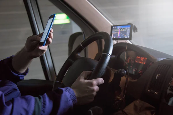 Close up of driving van driver. He is using mobile phone which is forbidden while driving.