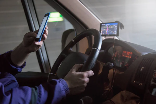 驾驶面包车司机的特写。他使用手机，严禁开车时. 图库图片
