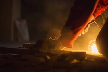 Fabrikada, açı değirmeni kullanarak çalışan ellerini yakın.