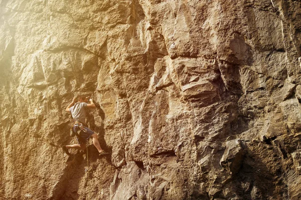 Uomo atletico arrampicata su roccia durante il tramonto . — Foto Stock