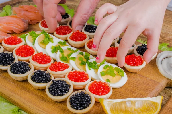 Tartaletas con caviar, huevo, cebolla y salmón en un corte de madera — Foto de Stock