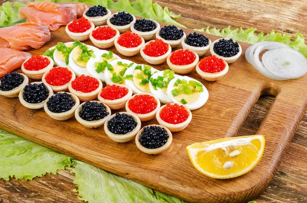 Tartaletas con caviar, salmón salado y huevos . — Foto de Stock