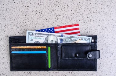 Bir banknot yüz dolar, siyah çanta ve bir Amerikan bayrağı.