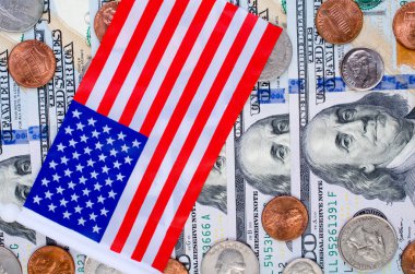 Banknot yüz dolar, çok sayıda sikke ve Amerikan bayrağı.