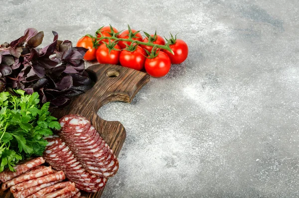 Geschnittene Salami, Kräuter und Tomaten liegen auf dem Küchentisch. — Stockfoto