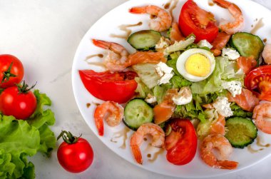 Sebze ve beyaz bir tabak karides salatası. Üzerinde hafif bir ba