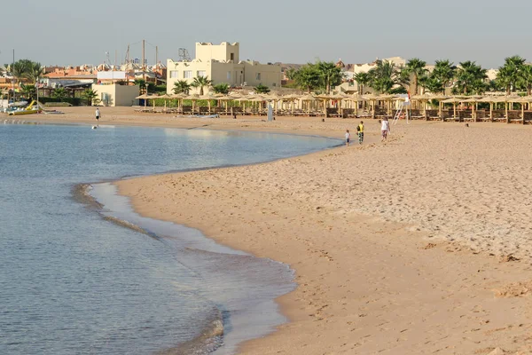 Ludzie chodzą wzdłuż bezludnej plaży nad brzegiem morza w tropica — Zdjęcie stockowe