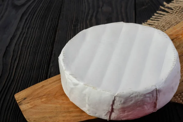 Round Camembert cheese on a wooden board with sack. — Stock Photo, Image