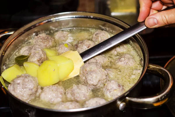 Preparation of homemade soup with meatballs and vegetables in a
