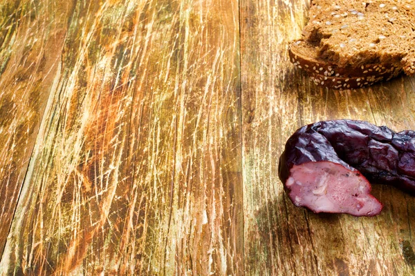 Smoked pork sausage with black bread on the rustical wooden back — Stock Photo, Image