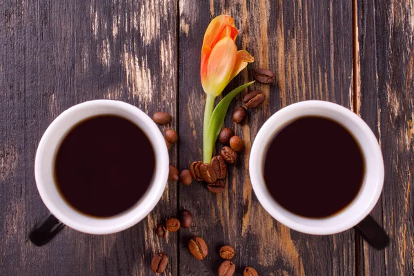 Zwei Tassen Kaffee und Kaffeebohnen auf dunklem Holzgrund. — Stockfoto