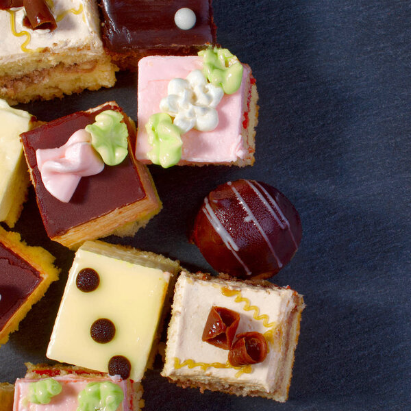 Assorted colorful natural sweet cakes on a black background. Cop