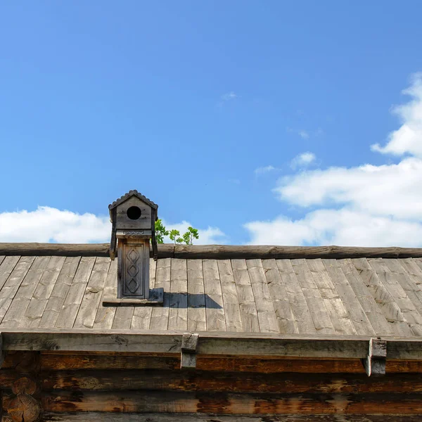 Old wooden rustic roof and chimney with birdhouse on the sky bac — Stock Photo, Image
