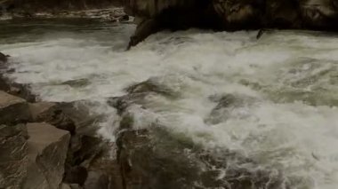 Açık nehir su akışı sıçraması ile beyaz ve şeffaf kabarcıkları ile akan. Güçlü şelale river rapids üzerinde. Video 4k. Yakın çekim.