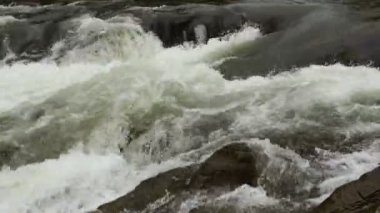 Açık nehir su akışı sıçraması ile beyaz ve şeffaf kabarcıkları ile akan. Güçlü şelale river rapids üzerinde. Video 4k. Yakın çekim.