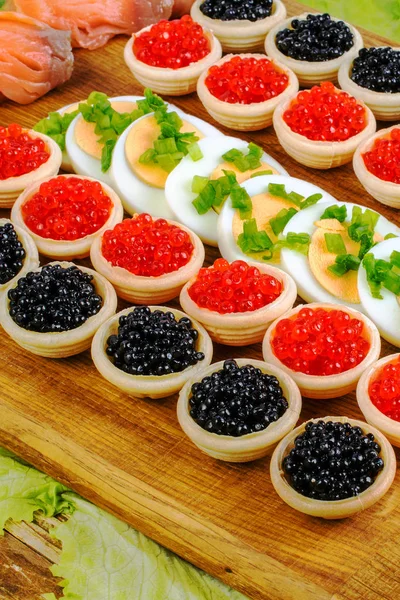 Homemade tartlets with red and black caviar, salmon, lettuce and — Stock Photo, Image