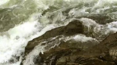 Açık nehir su akışı sıçraması ile beyaz ve şeffaf kabarcıkları ile akan. Güçlü şelale river rapids üzerinde. Video 4k. Yakın çekim.