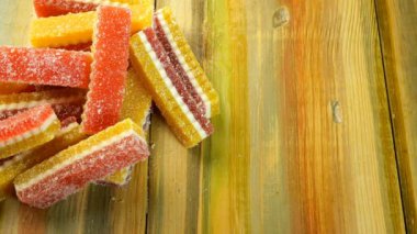 İnsan eli, ahşap zemin üzerinde duran çok renkli şeker marmelatını alır. Yakın plan..