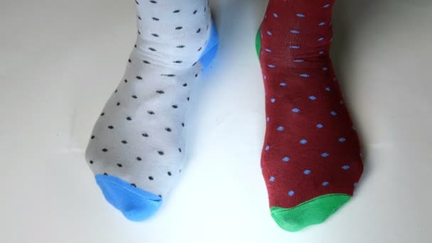 Menschenbeine in modischen Socken in verschiedenen Farben bewegen sich auf weißer, fester Oberfläche. Vielleicht tanzt er, treibt Sport oder Fitness. Nahaufnahme. — Stockvideo