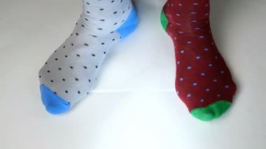 Farklı renkte, modaya uygun çoraplar giyen insan bacakları beyaz katı yüzeyde hareket eder, yürür ve tepinir. Belki dans ediyordur, spor yapıyordur ya da spor yapıyordur. Yakın plan..