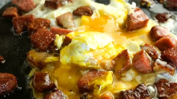 Cocinar deliciosos platos calientes. Huevos fritos o tortilla y picado, crujiente, salchicha con tocino se fríen en grasa caliente en la sartén de cocina . — Vídeo de stock