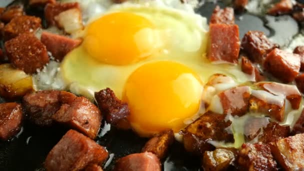 Matlagning läckra varma rätter. Stekta ägg eller omelett och tärnade, krispiga, korv med bacon steks i varmt fett i köket stekpanna. — Stockvideo