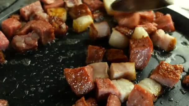 Cuisiner de délicieux plats chauds. Les dés, croustillants, les saucisses et le bacon sont frits dans de la graisse brûlante dans une poêle de cuisine . — Video