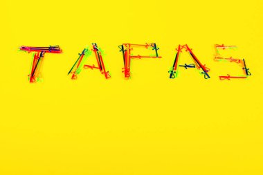 Sarı arka planda Tapas yazıtları var.