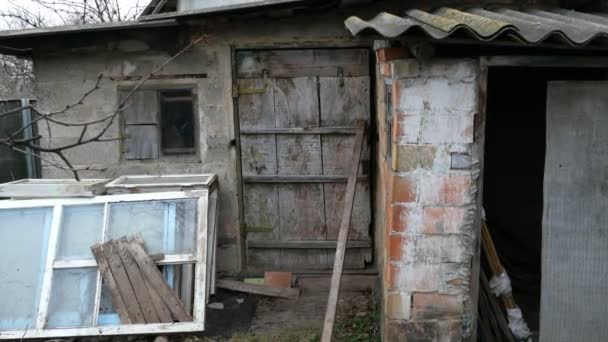 Obsoleto cobertizo de ladrillo abandonado con una estructura dañada y erosionada y puerta rota en una antigua granja o patio trasero rural. Primer plano . — Vídeo de stock