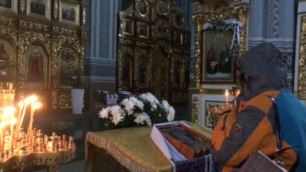 Kiev, Ucrania, enero de 2020: - La mujer mayor reza y es bautizada cerca de iconostasis e icono en la Iglesia Ortodoxa. Plan medio . — Vídeo de stock