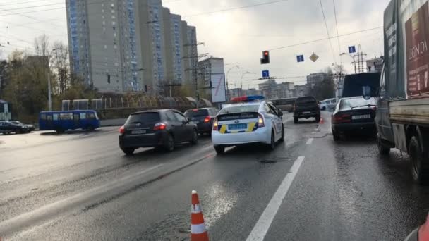 Kiev, Oekraïne, december 2019: - Politieauto op kruispunt bij stoplicht, afgeschermd met gestreepte zuilen. Stadsverkeer patrouilleren, documenten controleren, verkeersongeval formaliseren. — Stockvideo