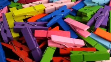 Many multi colored wooden clothespins in heap rotate in circle. Colorful background.