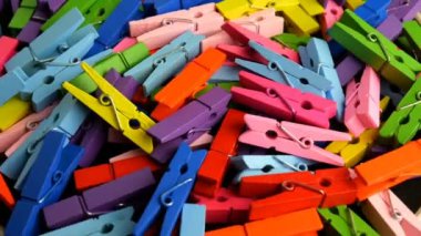 Many multi colored wooden clothespins in heap rotate in circle. Colorful background. Slow motion.