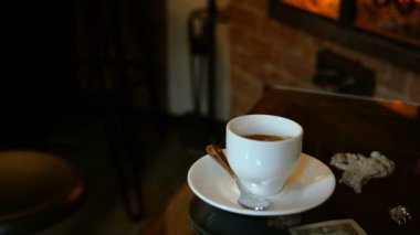 Kafede ya da şömineli restoranda bir fincan kahve var. Ateşin parıltıları masaya yansıyor. Romantik bir ortam. Seçici odaklanma. Ortam planı.