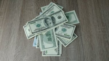 Eller ahşap bir masanın üzerine bir sürü dolar saçar. Yakın plan..